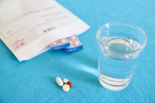 Medikamenten und Wasserglas auf blauer Fläche